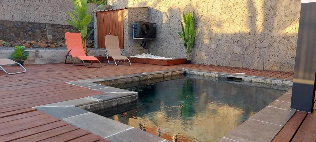 una piscina con 2 sillas y una terraza de madera en Villa Belle Vie - Climatisée & Piscine chauffée, en La Possession