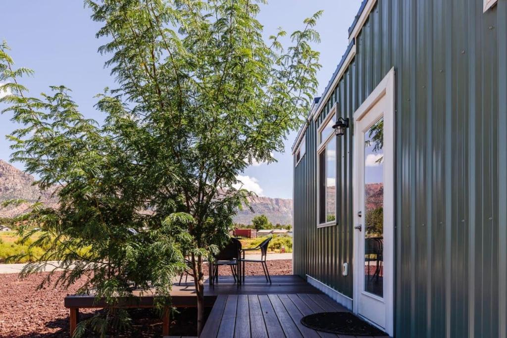 a deck with a tree and a house at Harrington Tiny House in Apple Valley