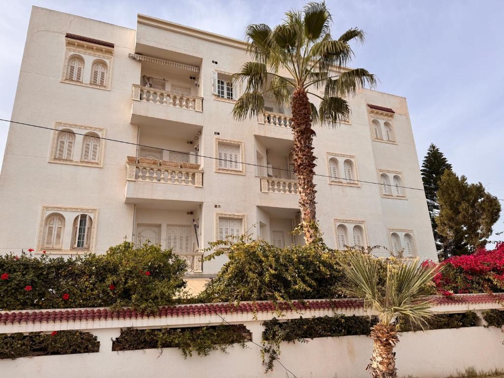 a building with a palm tree in front of it at Résidence TANTANA in Chott Meriem