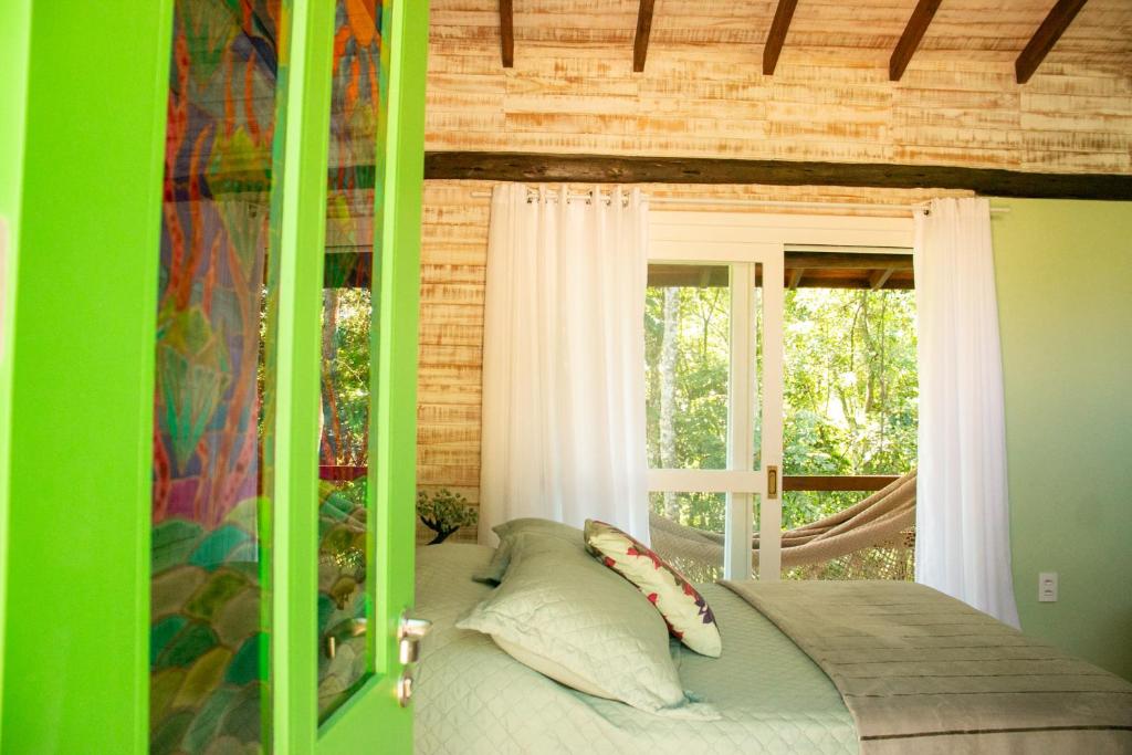 - une chambre avec un lit à baldaquin et une fenêtre dans l'établissement Chalé Esmeralda na Amarte perto do Templo Budista, à Três Coroas