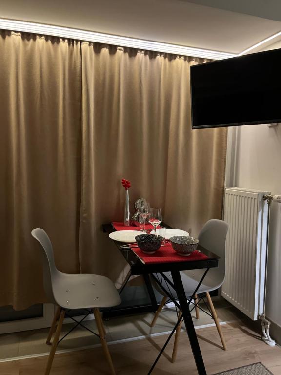 stół z dwoma białymi krzesłami i czerwony stół sidx sidx sidx sidx w obiekcie Nilton 2 Apartmans w Niszu