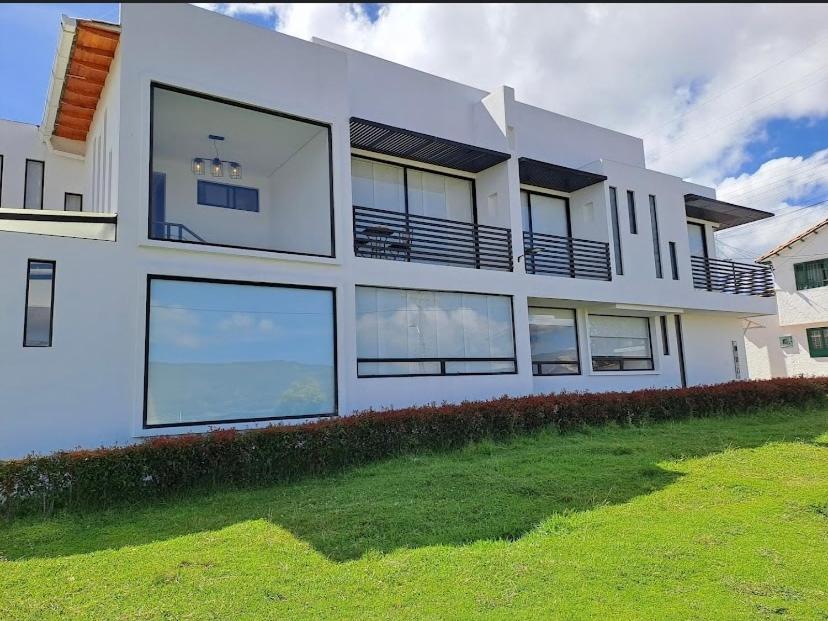 a large white house with large windows and a yard at Caminos del dorado sede apartamento in Guatavita