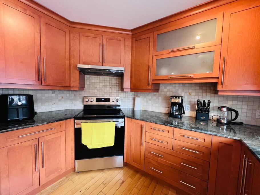 uma cozinha com armários de madeira e um forno com placa de fogão em Family-Friendly 3BR Home with Backyard em Montreal
