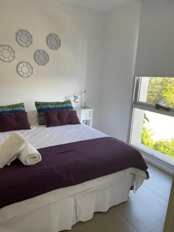 um quarto com uma cama grande e uma janela em Rinconada del Mar em Punta del Este