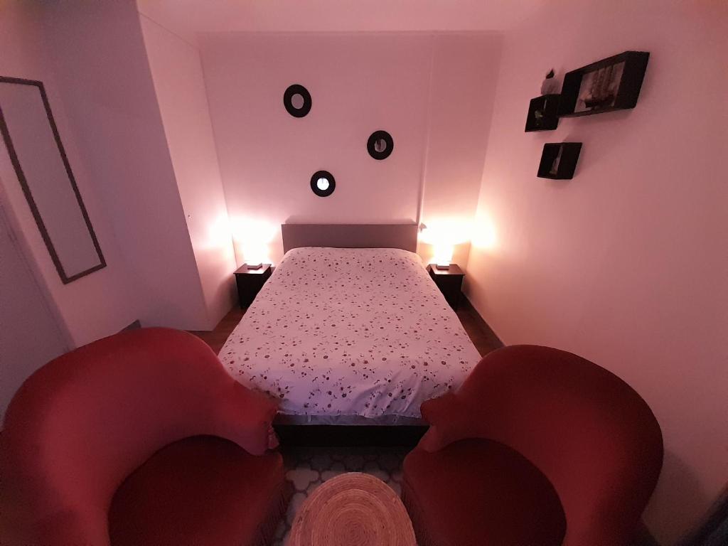 a bedroom with a bed and two red chairs at La Chaloupe 4 in Thiers