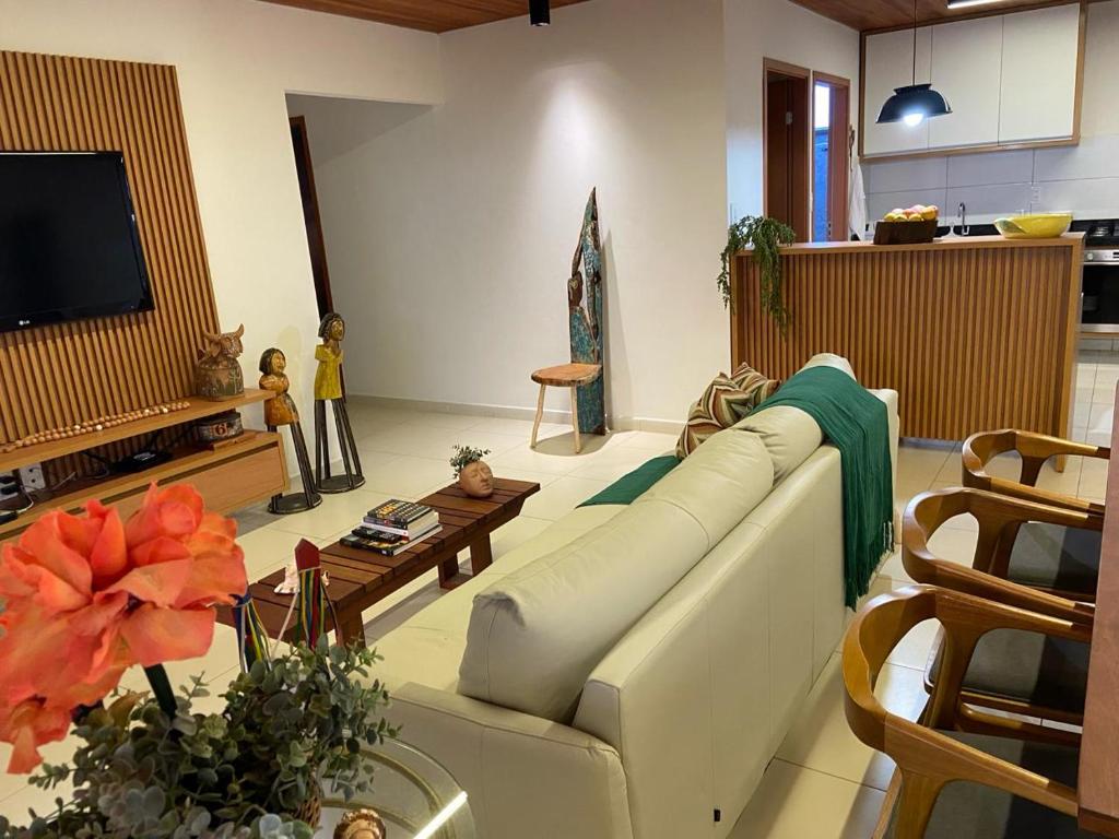 uma sala de estar com um sofá branco e uma televisão em CASA SONHO VERDE 5 QUARTOs 3 suítes CONDOMÍNIO BEIRA-MAR em Paripueira