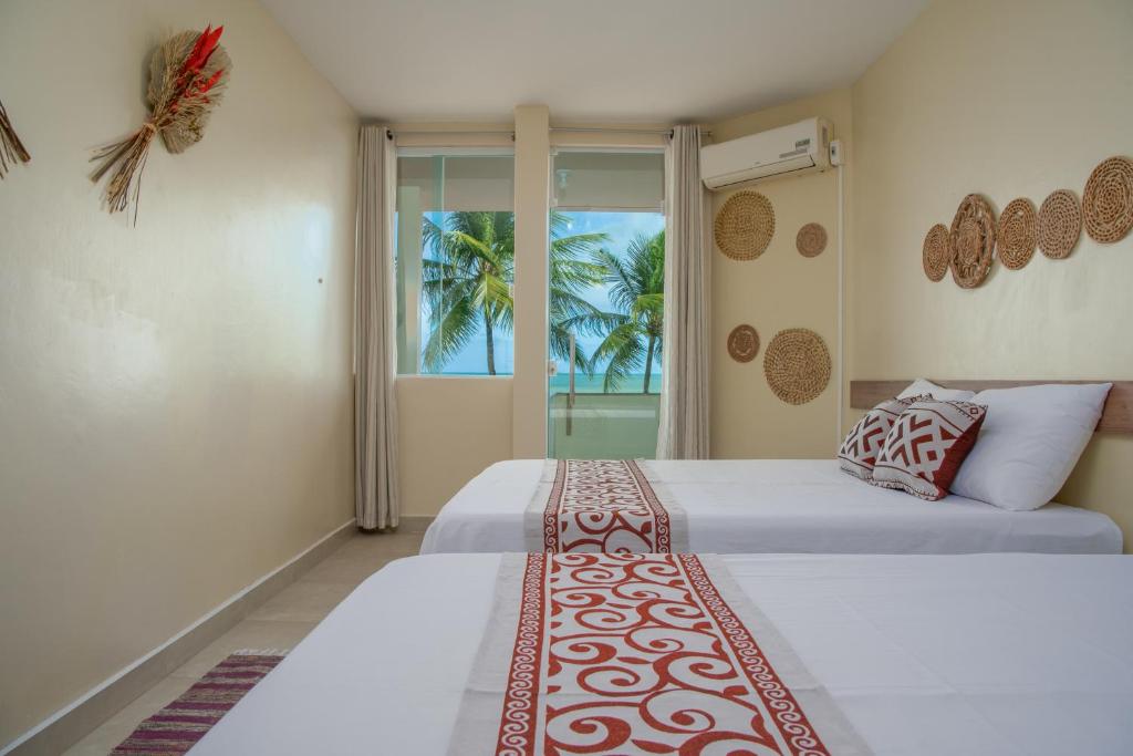 a bedroom with two beds and a window at Paraíso de Tabuba - casa de aluguel por temporada - 32km de Maceió-AL - Pé na areia - 24h de Frente para o mar in Barra de Santo Antônio
