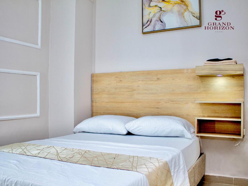 Schlafzimmer mit einem Bett mit einem Kopfteil aus Holz in der Unterkunft Hotel Grand Horizon Rodadero in Santa Marta