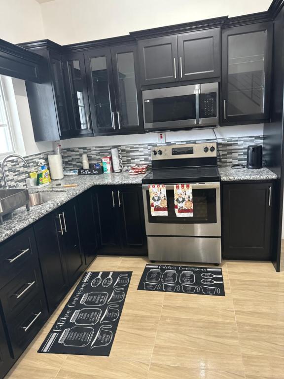 a kitchen with black cabinets and a stove top oven at Villas in A Gated Community in May Pen