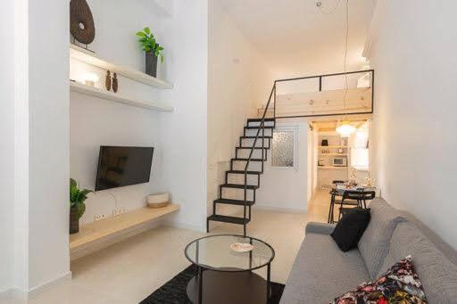 a living room with a couch and a tv and a staircase at CASA ALTA LOFT in Málaga