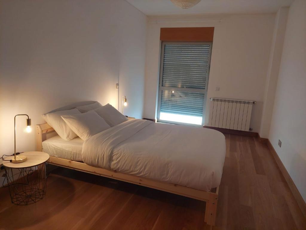 Schlafzimmer mit einem Bett, einem Tisch und einem Fenster in der Unterkunft Ramona in Aveiro
