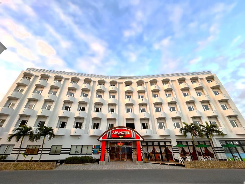 un gran edificio blanco con una señal de hotel delante en APA Hotel Ishigakijima, en Ishigaki Island