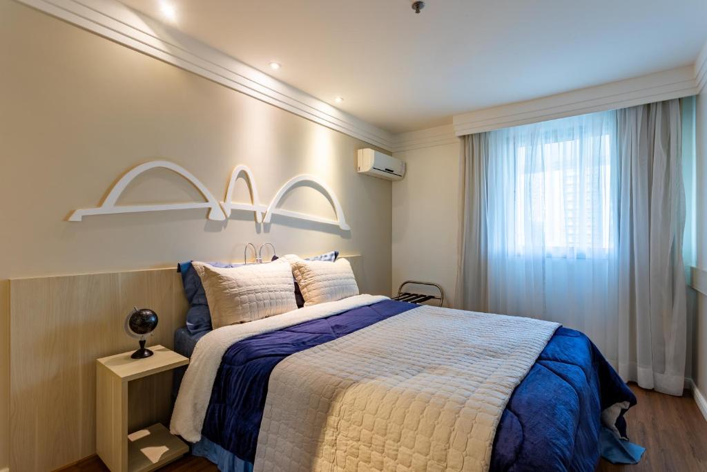 a bedroom with a large bed and a window at Flat Brasília 50m2 com varanda in Brasilia