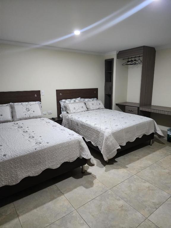 a bedroom with two beds with white comforters at HOTEL CASA MARED Corferias-Embajada Americana in Bogotá