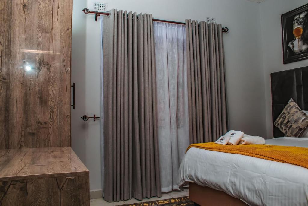 1 dormitorio con 1 cama y una ventana con cortinas en Luxury 2 Bed Self Catering Apartment in Masvingo, en Masvingo