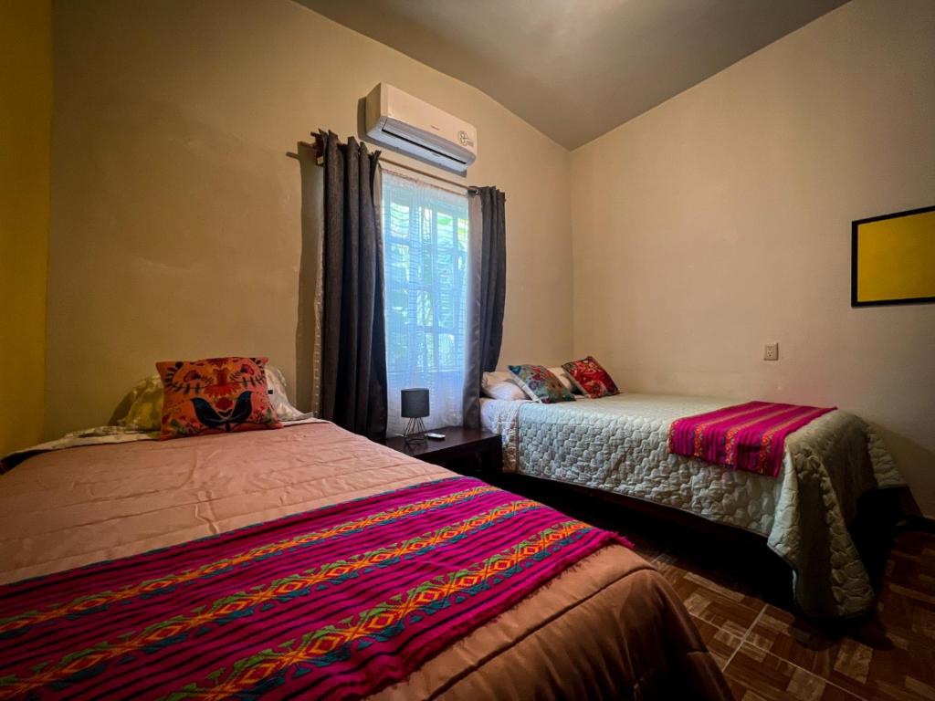 1 dormitorio con 2 camas y ventana en Casa de campo - Ruta Turquesa, en El Naranjo