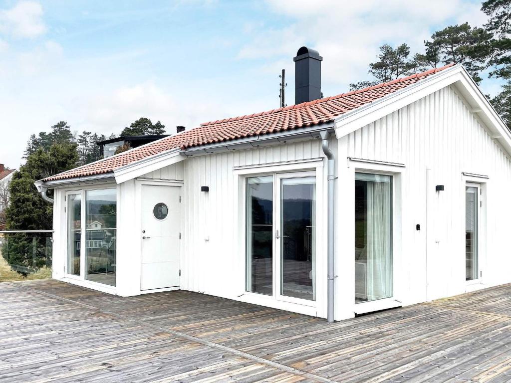 Holiday home UDDEVALLA XIX في Sundsandvik: منزل أبيض مع نوافذ كبيرة على سطح خشبي