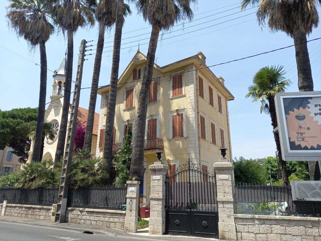 une maison jaune avec des palmiers devant elle dans l'établissement LA MASCOTTE, à Vallauris