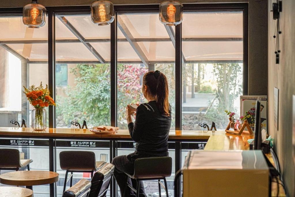 a woman sitting at a bar looking out the window at Noel Business Hotel in Busan