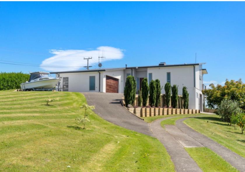 a house with a boat parked in the driveway at Tauranga Luxury Getaway in Tauranga
