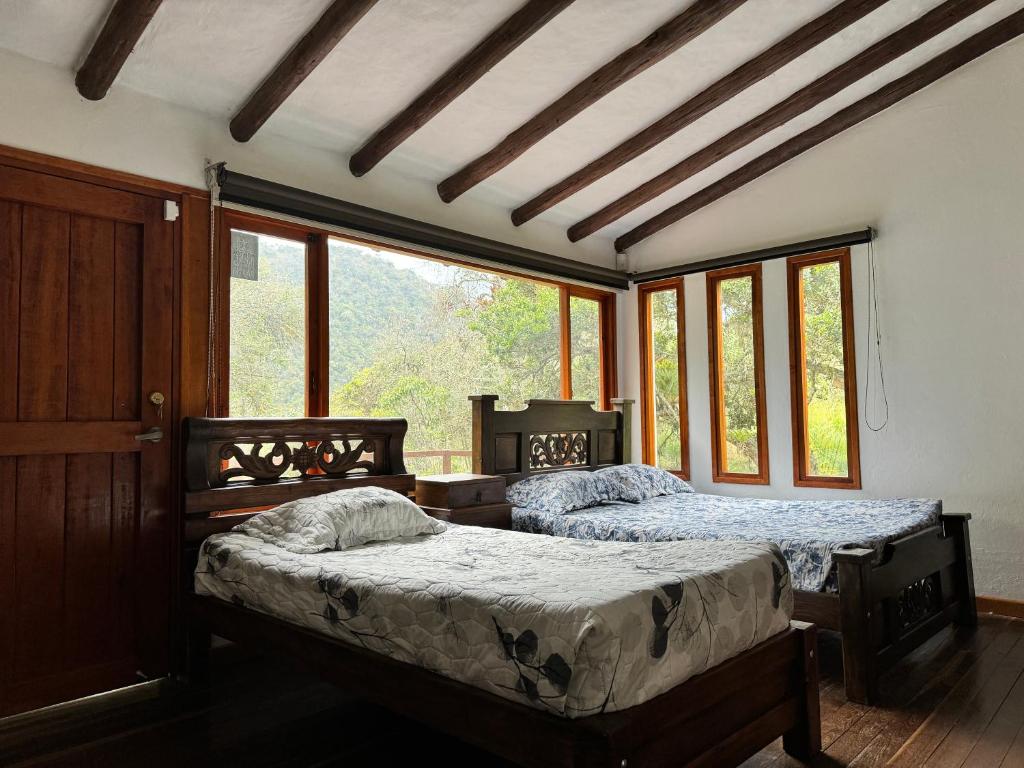 two beds sitting in a room with windows at Termales azules La Calera in El Salitre