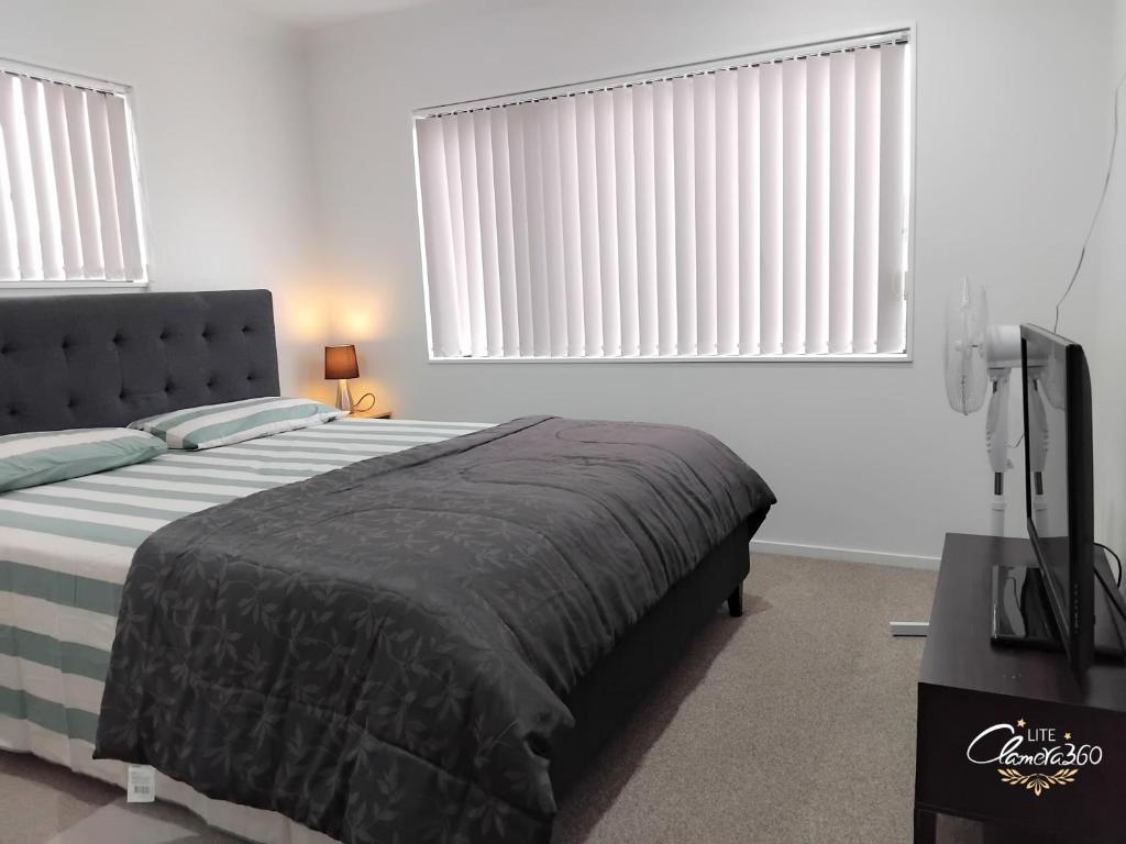 um quarto com uma cama e uma televisão de ecrã plano em HomeStay! Close to Airport, bus & Train station em Auckland