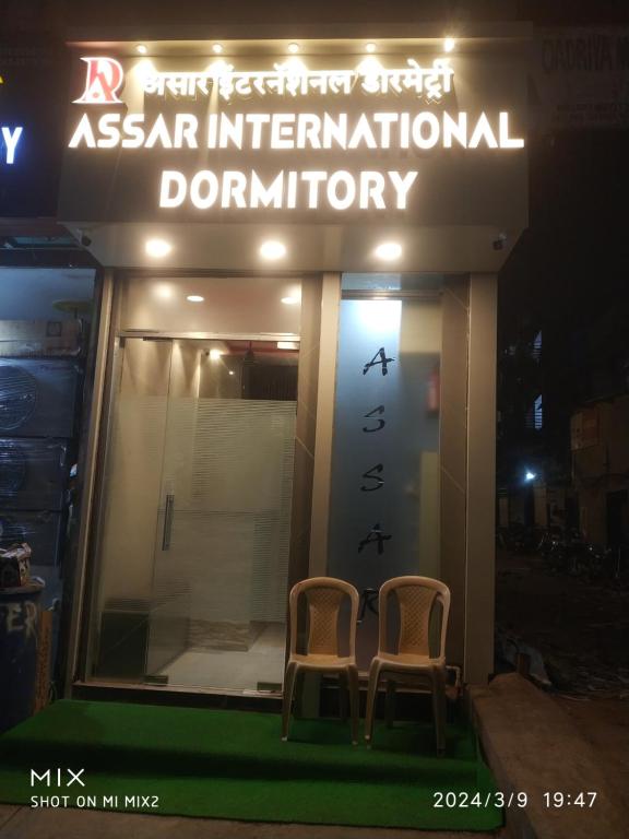 two chairs sitting outside of a restaurant at night at New Assar International dormitory in Mumbai