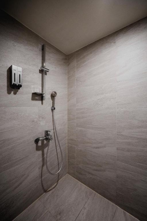 a bathroom with a shower with a hose on the wall at Hub Hotel Kaohsiung Yawan Branch in Kaohsiung