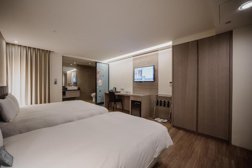 a hotel room with two beds and a desk at Hub Hotel Kaohsiung Yawan Branch in Kaohsiung
