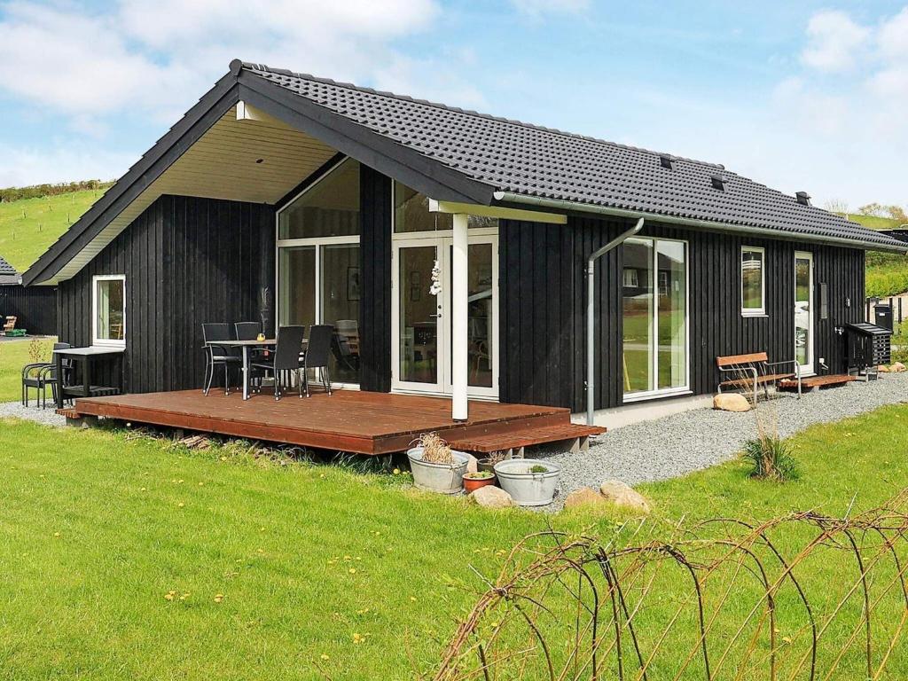 a black house with a wooden deck in a yard at 5 person holiday home in Haarby in Brunshuse