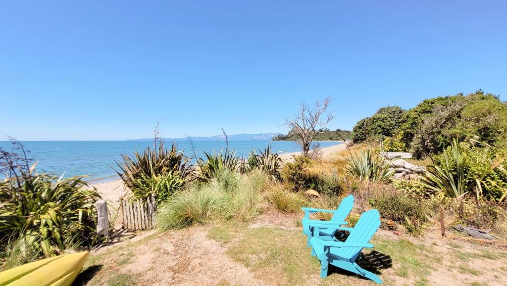 a blue chair sitting on the beach near the water at Parapara's Seaview Retreat in Parapara 
