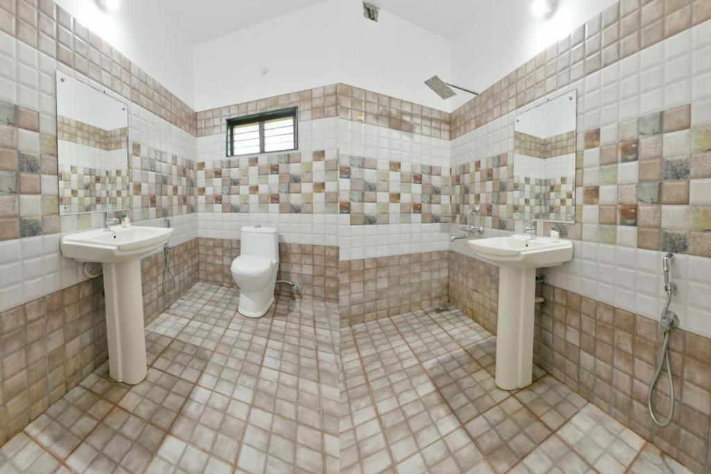 La salle de bains carrelée est pourvue de deux lavabos et de toilettes. dans l'établissement Hilton Beach Home, à Alappuzha