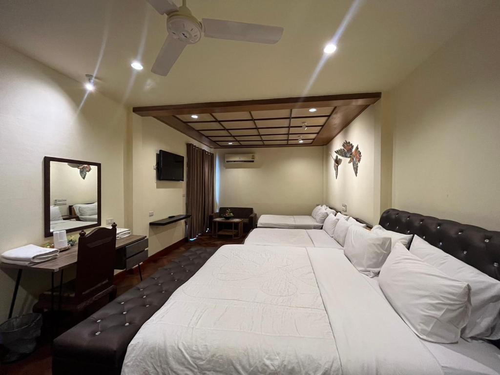 a hotel room with two beds and a desk at Prince Hotel Chiang Mai in Chiang Mai