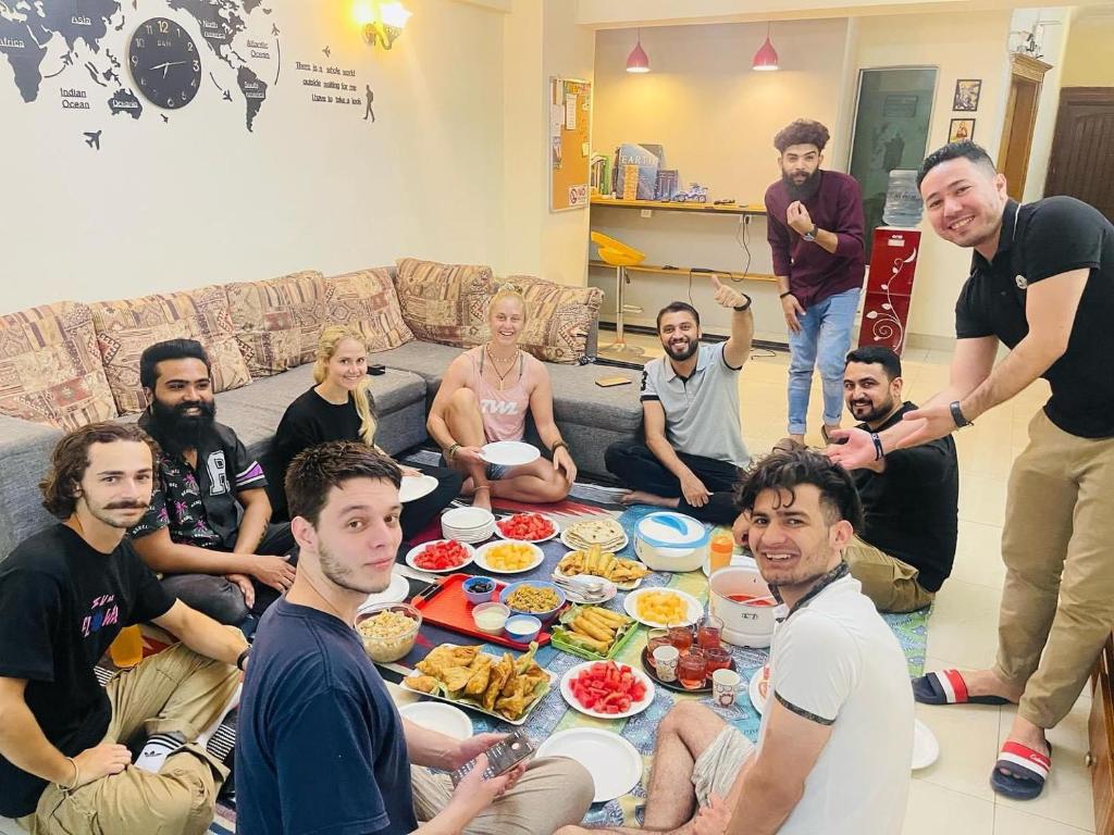 een groep mensen die rond een tafel zitten met eten bij Backpackers Hostel Islamabad in Islamabad