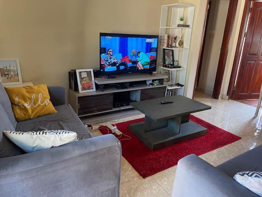 a living room with a flat screen tv and a table at Calm Haven: Your Private Retreat in Kira