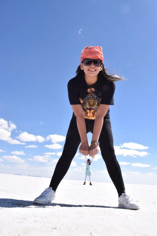 a woman standing on the beach with a person in the background at Beds of salt G in Potosí