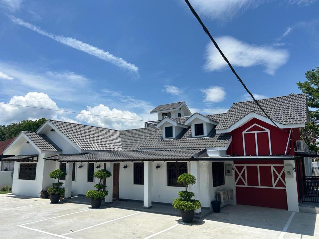 een rood-wit gebouw met een garage bij The Farmhouse in Ipoh