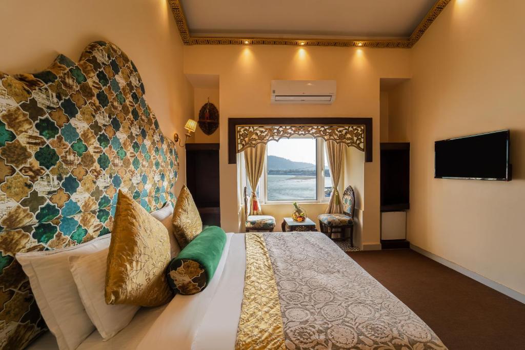 um quarto com uma cama grande e uma janela em The Neeraj Ganga Heritage Palace em Rishikesh