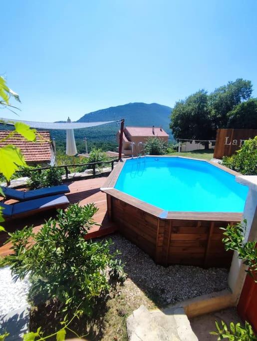 a large swimming pool in a yard with chairs around it at Old House Lapis- pool, hot tub, BBQ in Zadvarje