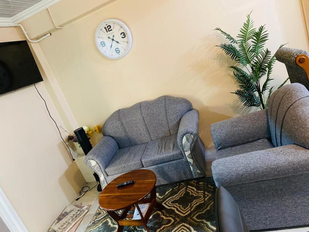 a living room with a couch and a clock on the wall at Destination Hope Booking in Georgetown