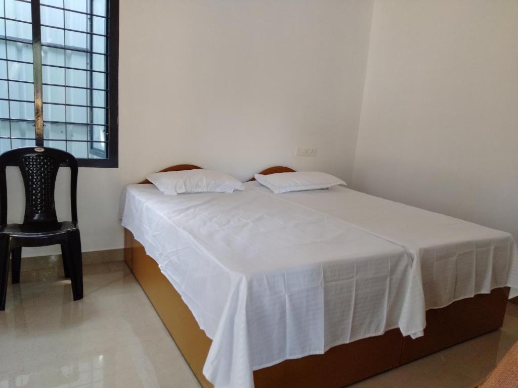 a bedroom with a white bed and a chair at Sambranikodi Lagoongate Resorts in Perumanseri