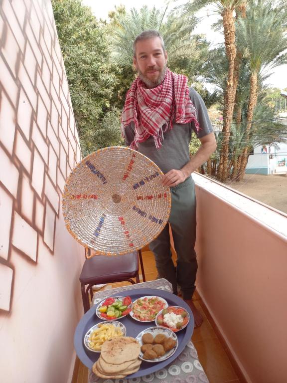 a man standing next to a table of food at charming nubian guest house in Aswan