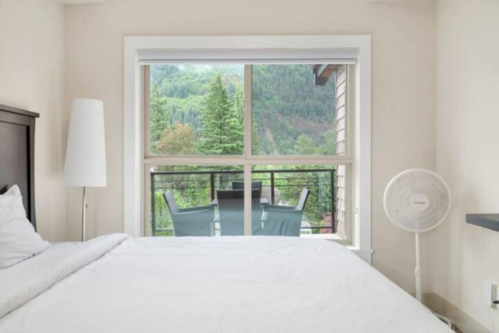 a bedroom with a white bed and a large window at Modern 4BR Penthouse w/Lake Views & Rooftop Deck in Harrison Hot Springs