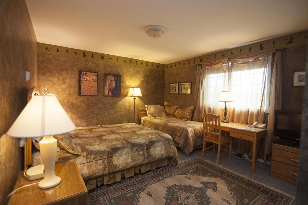 Habitación de hotel con 2 camas y escritorio en Midnight Sun Inn, en Whitehorse