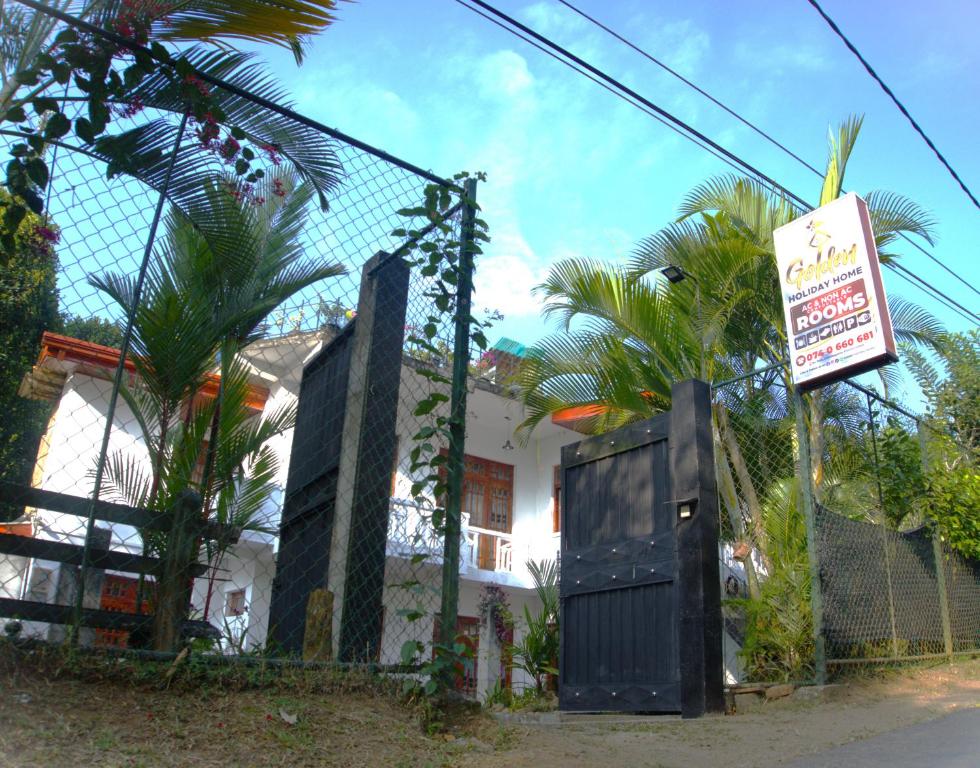 a fence with a sign in front of a house at golden holiday home peradeniya in Arambegama