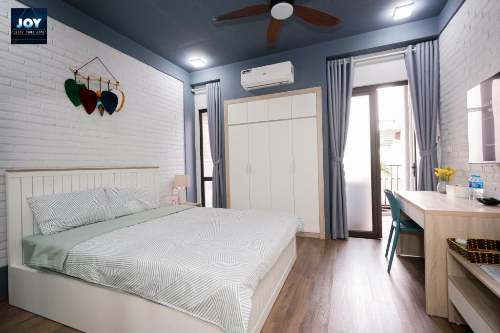 JOY APARTMENT TAY HO في هانوي: غرفة نوم بسرير ومروحة سقف