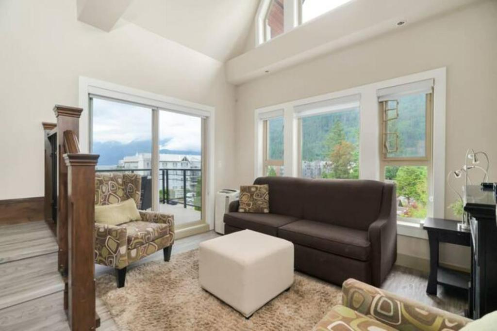 sala de estar con sofá, sillas y ventanas en 3BR Lakeside Dream Penthouse with Roof Deck Views, en Harrison Hot Springs