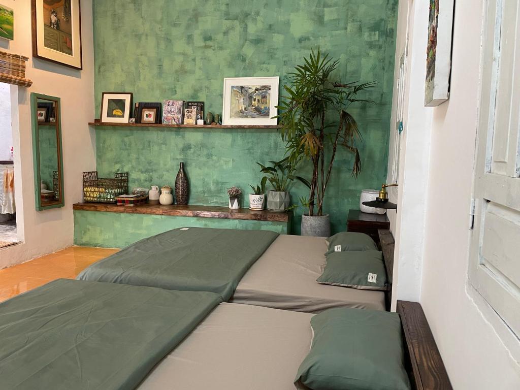 two beds in a room with green walls at Cọ cùn homestay/ Handmade/ Artwork (2 beds) in Buon Ma Thuot