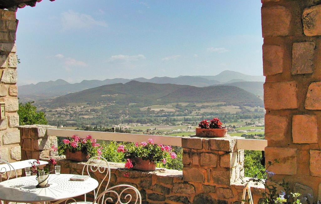 d'une terrasse avec une table, des chaises et des montagnes. dans l'établissement Le Mas Des Oiseaux, à Vaison-la-Romaine