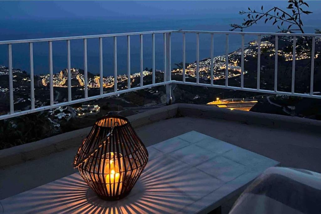 een lamp die 's nachts op een tafel op een balkon zit bij Mountain house with sea view in Ítrabo